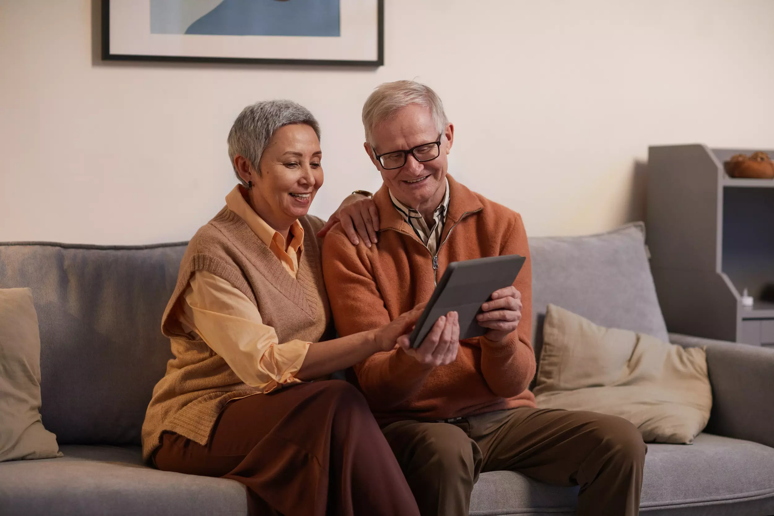 Man and woman sitting on a sofa while looking at a tablet computer